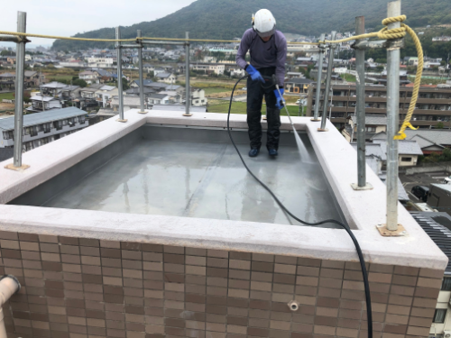 屋上を高圧洗浄する男性作業員